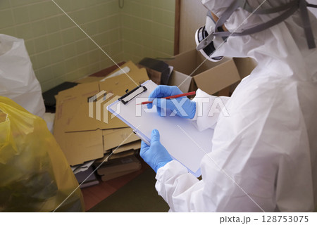 ゴミ屋敷清掃現場の防護服作業員 128753075