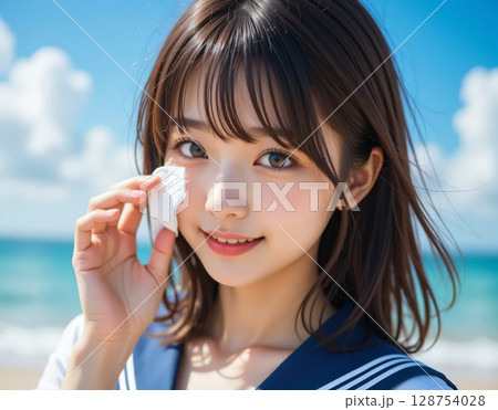 海の近くでボディシートで顔の汗を拭きとる女子高生 128754028