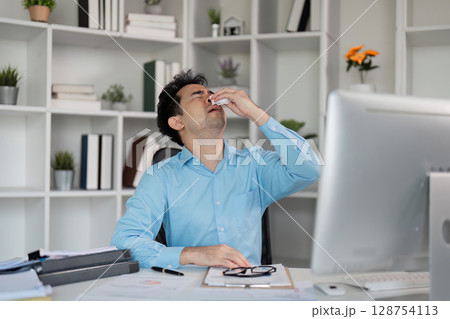 Unwell employee struggling with flu symptoms at office fever management techniques bright workspace close-up perspective Unwell employee struggling with flu symptoms at office fever management techniques bright workspace close-up perspective 128754113