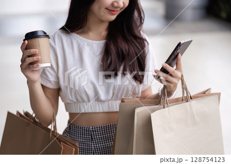Young Woman Enjoys Black Friday Shopping Spree with Multiple Bags and Coffee in Hand 128754123