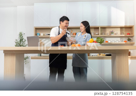 Couple Sharing Cooking Tips and Ingredients in Bright Kitchen Couple Sharing Cooking Tips and Ingredients in Bright Kitchen 128754135