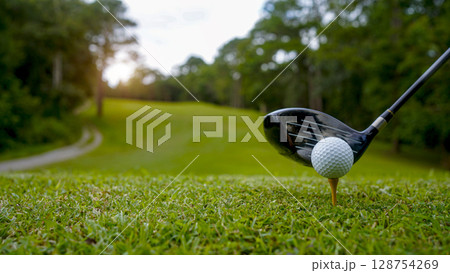 Golf clubs and golf balls on a green lawn in a beautiful golf course with morning sunshine. 128754269