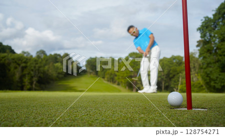 Golfer putting ball on the green golf, lens flare on sun set evening time. Golfer putting ball on the green golf, lens flare on sun set evening time. 128754271