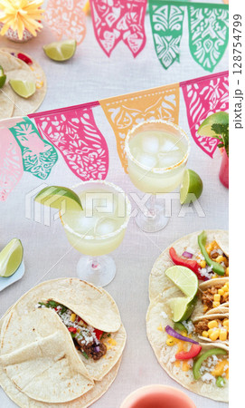 Cinco de Mayo celebration with tacos, drinks, and colorful decorations, food background 128754799