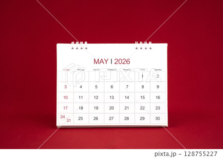 May 2026 white desk calendar stand on dark red color background. 128755227