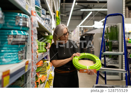 Woman selecting items in a hypermarket while engaged with products and showcasing genuine emotions Woman selecting items in a hypermarket while engaged with products and showcasing genuine emotions 128755529