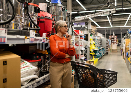 Woman choosing products in a hypermarket while exploring different departments for home essentials 128755603