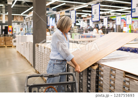 Middle-aged woman exploring home improvement store sections with shopping cart 128755693