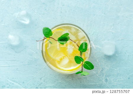 A glass of fresh lemonade, a mocktail with lemon juice, on a blue background A glass of fresh lemonade, a mocktail with lemon juice, on a blue background 128755707