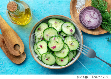 Cucumber salad with olive oil, dill, and red onion, on a blue background Cucumber salad with olive oil, dill, and red onion, on a blue background 128755709
