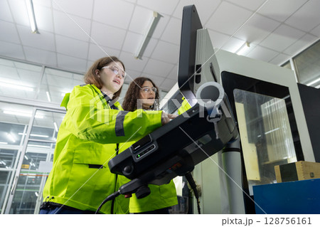 women engineer using computer control panel cnc machine at workshop. technician Female control automated machine process programming cnc machine at industry manufacturing. heavy industrial. 128756161