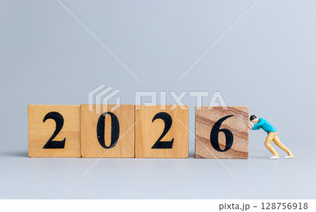 Miniature figure pushes wooden block to reveal 2026 Miniature figure pushes wooden block to reveal 2026 128756918