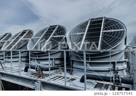 Cooling fans are installed on rooftop of large commercial building. Maintaining air circulation and temperature control. Tower air chiller HVAC. 128757345