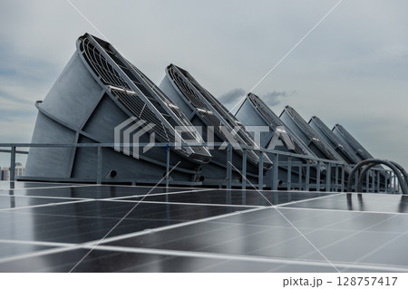 Cooling fans are installed on rooftop of large commercial building. Maintaining air circulation and temperature control. Tower air chiller HVAC. 128757417