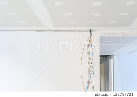 During interior renovation new gypsum board ceiling is installed showcasing smooth edges Building improvements include plastering ceilings where electrical wire preparation is complete During interior renovation new gypsum board ceiling is installed showcasing smooth edges Building improvements include plastering ceilings where electrical wire preparation is complete 128757721