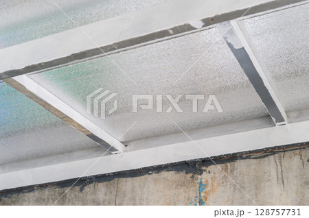 Structural metal beams support composite panel sheet made with insulation pu foam providing efficient thermal barrier often seen construction industrial building 128757731
