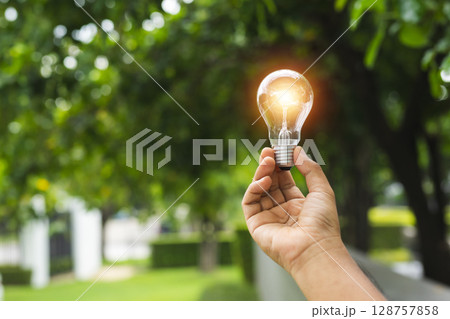 Hand holding Light bulb with light flare green nature background. eco innovation environmental and creative concepts. copy space banner. 128757858
