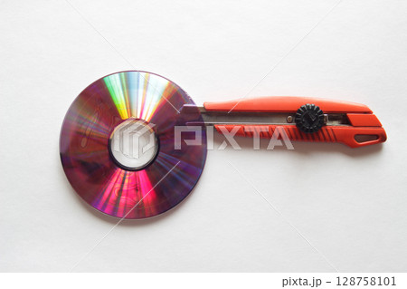 DVDディスクの接合部分の間にカッターナイフの刃を入れる 128758101