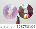 接合部分で二つに割ったDVDディスクとカッターナイフの刃先 接合部分で二つに割ったDVDディスクとカッターナイフの刃先 128758104