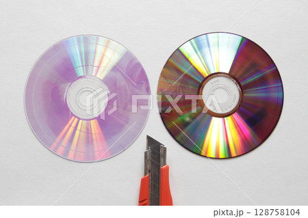 接合部分で二つに割ったDVDディスクとカッターナイフの刃先 128758104