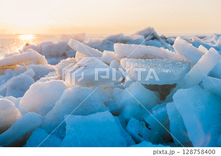 Frozen sea with stacked ice slabs at sunset, winter landscape of broken crystalline layers. Frozen sea with stacked ice slabs at sunset, winter landscape of broken crystalline layers. 128758400