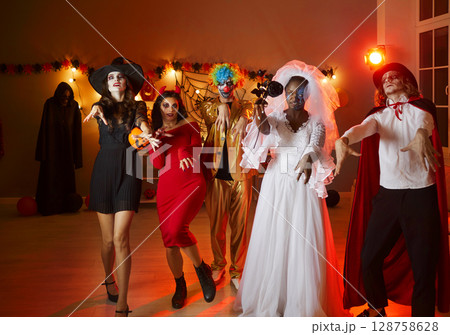 Group of friends in various Halloween spooky costumes pretend that they are walking dead. Group of friends in various Halloween spooky costumes pretend that they are walking dead. 128758628