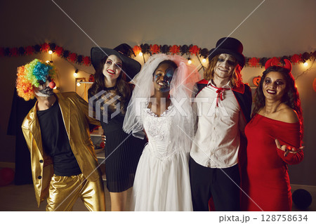 Portrait of multiracial adult friends in spooky costumes for Halloween at home party. 128758634