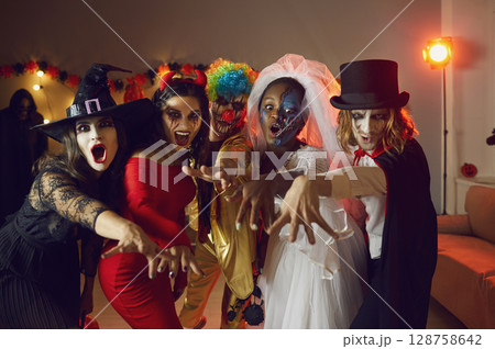 Group portrait of young friends in spooky Halloween costumes saying BOO all together 128758642