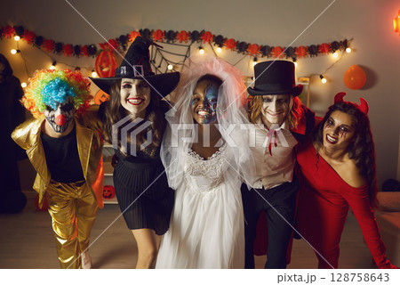 Portrait of group of young cheerful and crazy friends having fun at Halloween party. Portrait of group of young cheerful and crazy friends having fun at Halloween party. 128758643