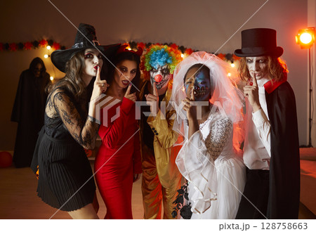 People in Halloween costumes holding fingers on lips asking you keep silent about their party 128758663
