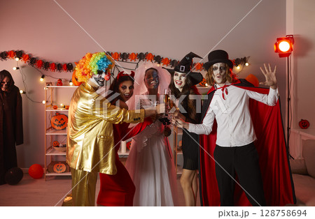Group of happy young people drinking and having fun at a Halloween party at home Group of happy young people drinking and having fun at a Halloween party at home 128758694