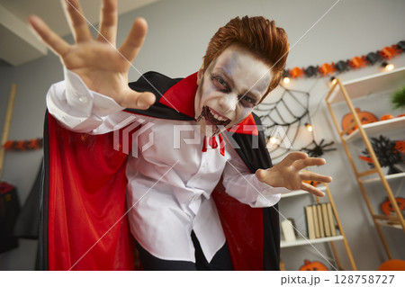 Portrait of a boy in a spooky vampire costume and scary makeup on Halloween night Portrait of a boy in a spooky vampire costume and scary makeup on Halloween night 128758727