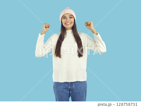 Cheerful positive young woman standing with her fists raised Cheerful positive young woman standing with her fists raised 128758731