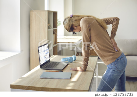 Woman who works in sitting posture on her computer all the time suffers from back pain Woman who works in sitting posture on her computer all the time suffers from back pain 128758732