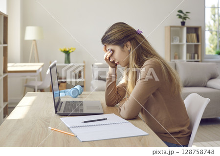 Bored frustrated female student tired of studying, working on laptop or sitting at home. 128758748