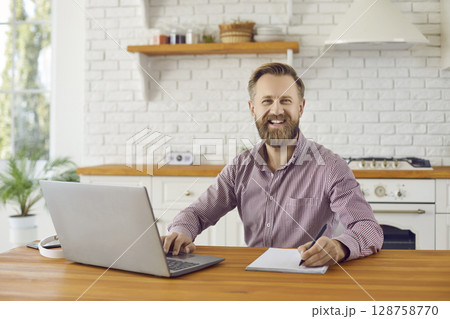 Portrait of smiling businessman work on computer at home 128758770