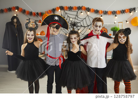 Group of children dressed in spooky Halloween costumes standing together and smiling 128758797