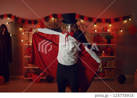 Adult man dressed up in a red and black vampire cloak for a spooky Halloween party 128758918