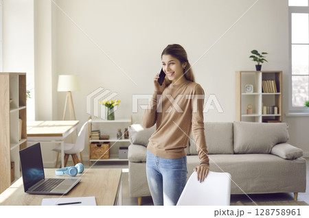 Young female business owner dropshipping at home talking on mobile phone and taking orders. 128758961