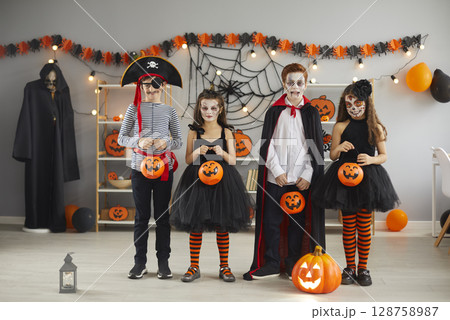 Group of children in carnival costumes with spooky makeup standing with buckets for candy. Group of children in carnival costumes with spooky makeup standing with buckets for candy. 128758987