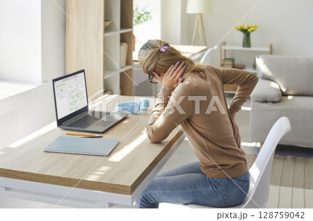 Woman who works in sitting posture on her laptop computer is suffering from back pain Woman who works in sitting posture on her laptop computer is suffering from back pain 128759042