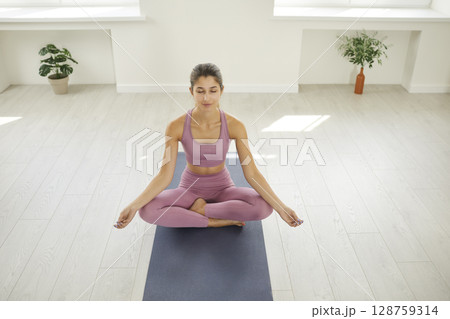 Portrait of relaxed athletic young woman enjoying meditation in yoga class at gym. Portrait of relaxed athletic young woman enjoying meditation in yoga class at gym. 128759314