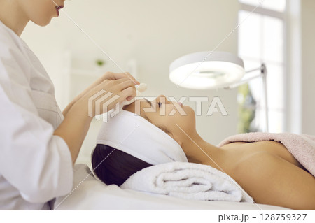 Beautician make face cleaning procedures to female client Beautician make face cleaning procedures to female client 128759327