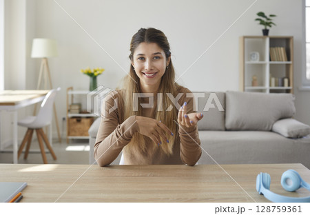 Webcam portrait of happy woman sitting at desk and talking to someone on video call 128759361