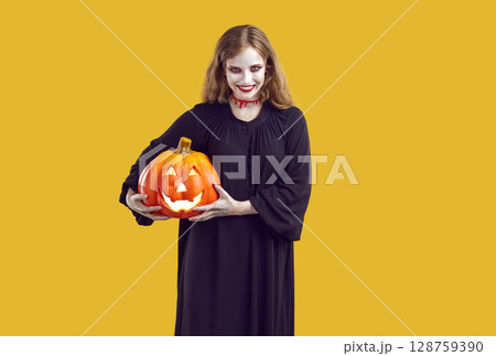 Halloween portrait of mad, spooky and evil woman with glowing jack-o-lantern in hands. Halloween portrait of mad, spooky and evil woman with glowing jack-o-lantern in hands. 128759390