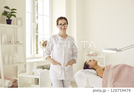 Portrait of friendly female woman beautician, aesthetic nurse or masseuse at her workplace. Portrait of friendly female woman beautician, aesthetic nurse or masseuse at her workplace. 128759479