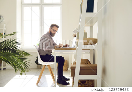 Serious focused businessman working on important work project in his bright home office. Serious focused businessman working on important work project in his bright home office. 128759488