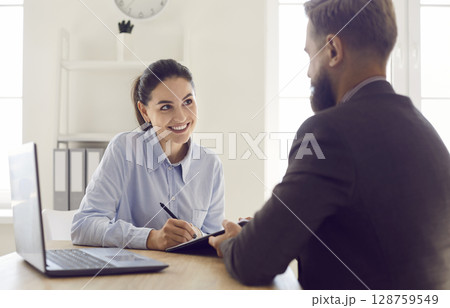 Smiling loan broker, insurance advisor or real estate agent talking to her client Smiling loan broker, insurance advisor or real estate agent talking to her client 128759549
