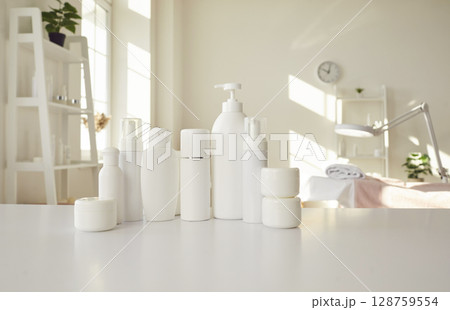 Set of different white clean bottles with natural cosmetics standing on table of beauty salon. 128759554