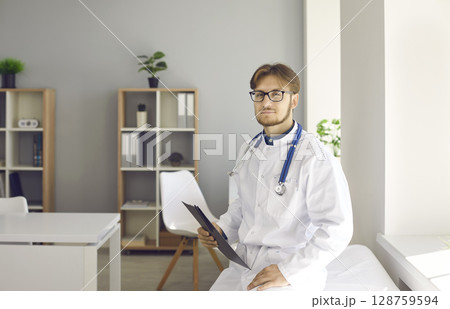 Portrait of male doctor in white coat in hospital 128759594